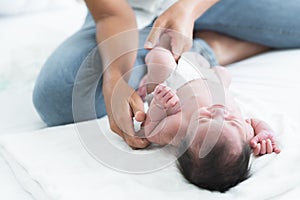 Selective focus on mother finger of Asian Australian newborn baby sleeping while her mom is changing diapers and clothes little