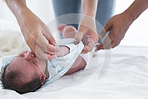 Selective focus on mother hand of Asian Australian newborn baby sleeping while her mom is changing diapers and clothes little baby