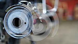 Selective focus on a motorcycle silencer end cap with blurred workshop background