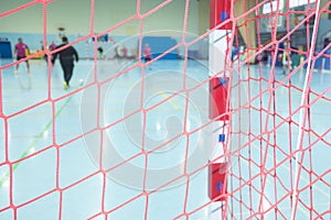 selective focus, netting of an indoor soccer goal with the players of the match out of focus in the background during a