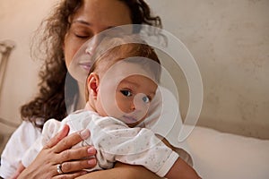 Selective focus on a newborn baby in the hands of a delightful woman, a happy loving mother gently hugging her baby boy.