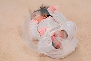 Selective focus newborn baby`s wearing bodysuit with diaper comfortable lying at home, newborn chubby leg bodypart movement in be