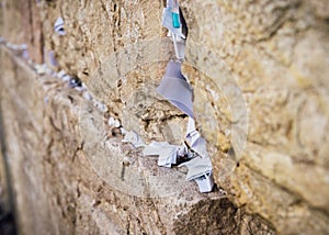 Selective focus on notes to God in the cracks between the bricks of the Western Wall, also known as Kotel, in the old photo