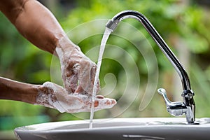 Selective focus of the old man hand image washing with dishwashing liquid and clean water on the sinks in the house near garden to