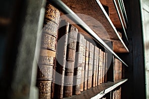 Selective focus of old, thick books on the wooden shelf with blurred background