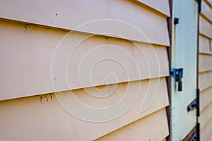 Selective focus of an old yellow old weatherboard wall and a bolted door