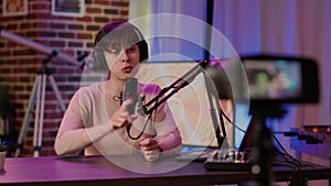 Selective focus on online radio host talking in front of digital camera recording vlog sitting at desk