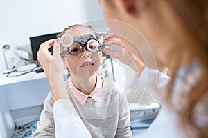 selective focus of ophthalmologist examining kid eyes with trial frame