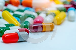 Selective focus on orange-gray antibiotic capsule pill on blurred background of colorful capsule pills. Pharmaceutical industry.