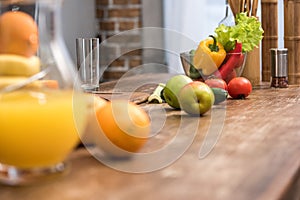 selective focus of orange juice in glass jug, fresh fruits and vegetables