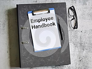 Selective focus paper clipboard written employee handbook with pen,ring file and eye glasses.
