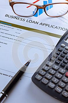 selective focus pen,Business loan application form,chart,glasses ,calculator,red paper clip on wood background.