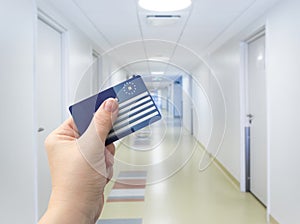 Selective focus on person hand holding blank European Health Insurance Card inside medical hospital.