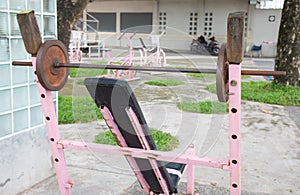 Selective focus and perspective view of old, grunge and rusty barbell equipment in the public outdoor gym which is free of charge