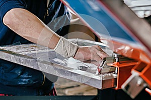 Selective focus photo of male hand with squeegee. serigraphy production. printing images on t-shirts by silkscreen method in a