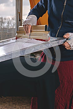 Selective focus photo of male hands with squeegee. serigraphy production. printing images on t-shirts by silkscreen method in a