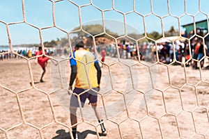 Selective focus photo of an unrecognizable goalkeeper protecting the goal during a soccer game on a beach in Masachapa