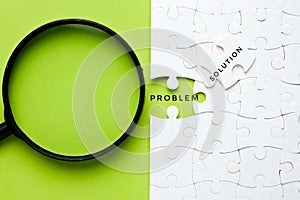 Selective focus picture of problem and solution word at jigsaw with magnifying glass insight.