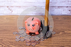Selective focus of a pink ceramic piggy together with a hammer and euro coins