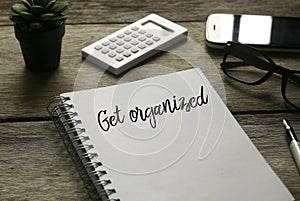 Selective focus of plant,calculator,mobile phone, glasses,pen and notebook written with ` Get Organized ` on wooden background