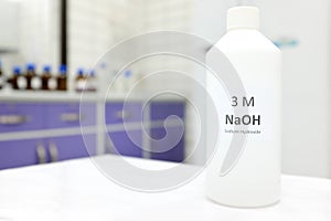 Selective focus of a plastic bottle of sodium hydroxide solution or NaOH chemical reagent. Chemistry research laboratory.