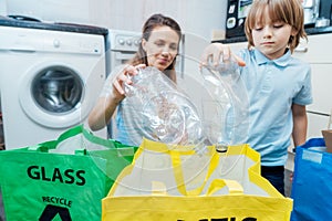 Selettivo concentrarsi sul plastica bottiglie da raccolta differenziata. madre un figlio sul tipo spazzatura diverso cestino sul 