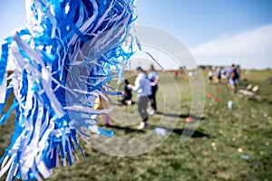 Selective focus on a pom-pom streamer with defocused child running in the background