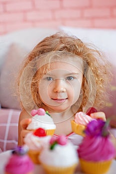 Selective focus. Portrait of a cute charming Caucasian blonde with cakes in the foreground