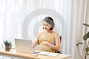 Selective focus of pregnant woman using laptop while working from home