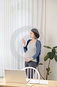 Selective focus of pregnant woman using laptop while working from home