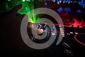 In selective focus of Pro dj controller.The DJ console deejay mixing desk at music party in nightclub with colored disco lights.