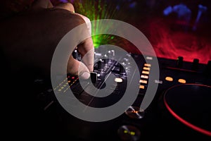 In selective focus of Pro dj controller.The DJ console deejay mixing desk at music party in nightclub with colored disco lights.