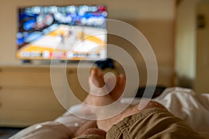 Selective focus on propped up feet with a blurred basketball game on the TV