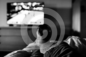 Selective focus on propped up feet with a blurred basketball game on the TV