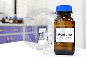 Selective focus of pure acetone solution in brown glass amber bottle inside a chemistry laboratory. White background. photo