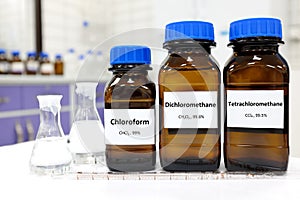 Selective focus of pure dichloromethane, chloroform and tetrachloromethane liquid chemical compound set in dark glass bottles.