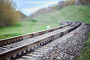 Selective focus railway track turns and twists between hills. Empty rounding and turning single track of railways