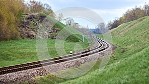 Selective focus railway track twists and turns between hills. Empty rounding and turning single track of railways