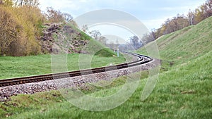 Selective focus railway track twists and turns between hills. Empty rounding and turning single track of railways