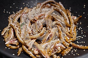 Selektívny sústrediť na surový nakrájaný ucho z bravčové sypané sezam semená v vyprážanie panvica. ázijský kuchyňa 