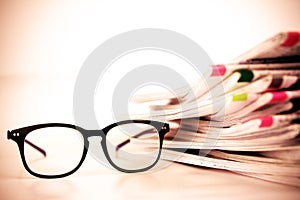 Selective focus on reading eyeglasses with stacking of newspaper