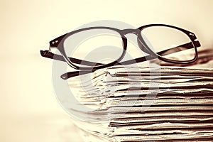 selective focus on reading eyeglasses with stacking of newspaper