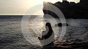 Selective focus. Rear view of a young beautiful caucasian woman practicing yoga on the beach at sunset by the sea. Yoga