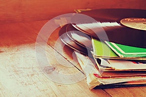 Selective focus of records stack with record on top over wooden table. vintage filtered