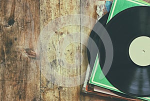 Selective focus of records stack with record on top over wooden table. vintage filtered