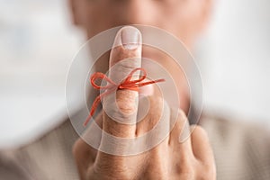 selective focus of red bow on finger of senior man with mental illness.