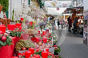 Red decorated candles and Christmas ornament sale in front of stall.