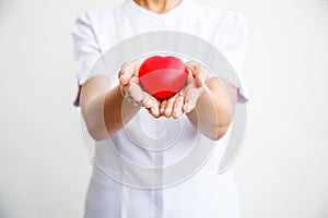 Selective focus of red heart held by female nurse`s both hand, representing giving all effort to deliver high quality service mind