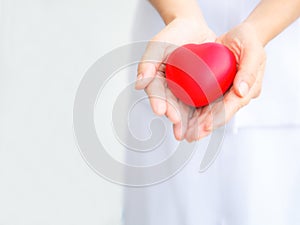 Selective focus of red heart held by female nurse`s both hand, representing giving all effort to deliver high quality service mind