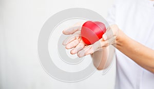 Selective focus of red heart held by female nurse`s both hand, representing giving all effort to deliver high quality service mind